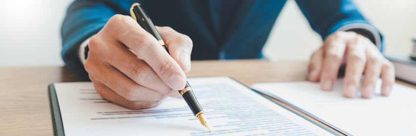 man signing paper with fountain pen